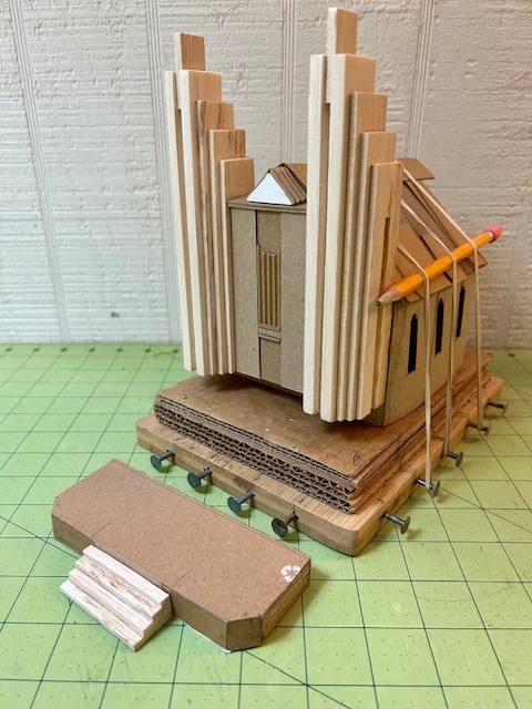 work in progress...raw cardboard and balsa...sitting on jig to hold roof in place while glue dries...front entry steps were changed after this photo taken...